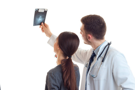 一个年轻的女孩和一名医生回相机站和她在一起，看着 x 射线