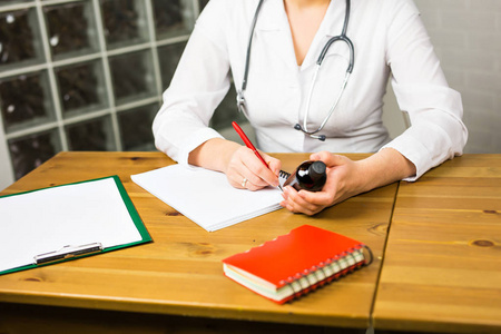 健康处方女医生医学医生或药剂师坐在工作表 手拿罐子或瓶子里的药丸