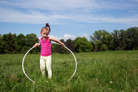 微笑与呼啦圈享受美丽的春天的一天在公园里的小女孩