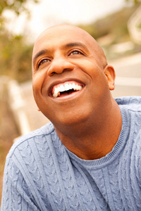 成熟的非洲裔美国人，微笑着坐在外面