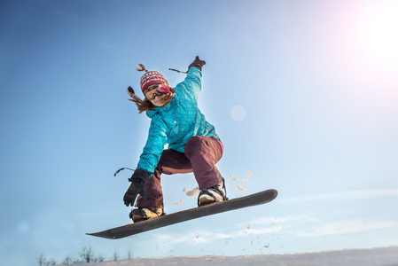 年轻的女子在滑雪板跳跃