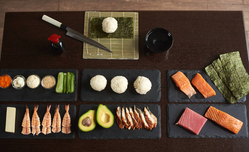 准备滚动寿司。用刀竹垫碗等黑石板上的配料。从顶部查看