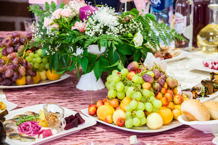 宴会上招待的餐桌。餐馆里有水果小吃美味佳肴和鲜花。庄严的事件或婚礼