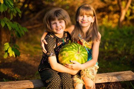 快乐的孩子在阳光明媚的日子里抱着非常大的西瓜。健康饮食理念