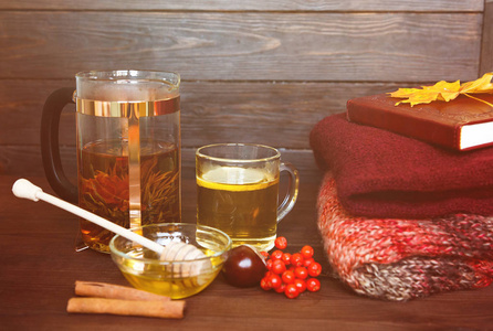茶和秋舒适。一杯茶, 蜂蜜, 一本书, 一张温暖的毯子和枫叶创造了秋天的心情。秋天的茶在一个木质的背景。温馨家居