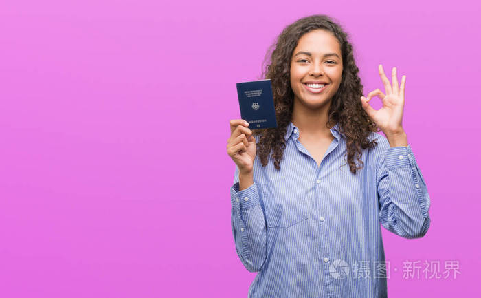 持有德国护照的年轻西班牙裔妇女做 ok 标志用手指, 优秀标志