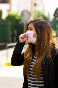 心情不好在空气污染，城市的背景下的城市街道上的防护面具的年轻女子