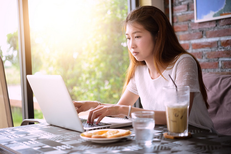 亚洲女人使用笔记本电脑在咖啡厅