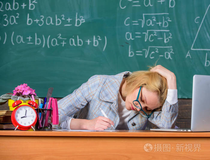 女教师坐桌教室黑板背景.还在工作工作远远超过实际的学校一天.