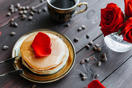 早餐咖啡和煎饼着玫瑰的桌子上