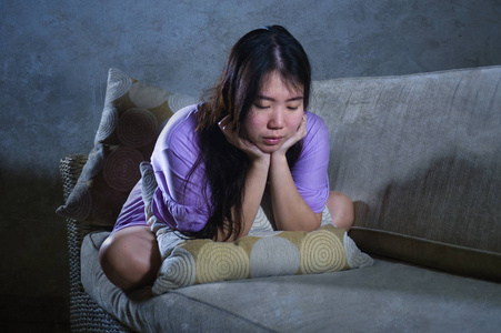 发痛年轻的悲伤和沮丧的亚洲华人妇女独自哭泣绝望地坐在家里沙发痛和
