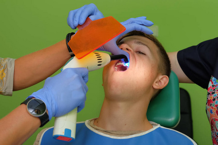 医生手里拿着蓝色的手套贴在青少年牙齿上的支架上。
