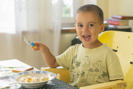 快乐的小男孩吃粥。小男孩吃早餐在桌