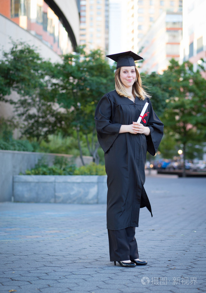 画像的女大学生在毕业帽和穿上长袍浩