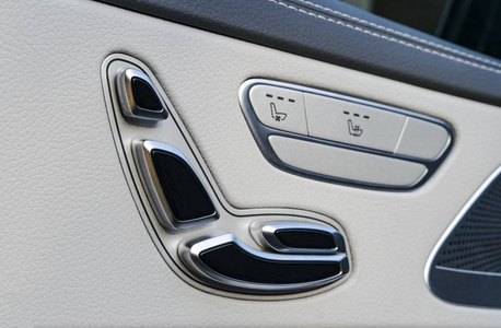 一辆豪华客车的电动座椅控制按钮的门把手。白色皮革内饰的豪华现代汽车。现代汽车内饰细节