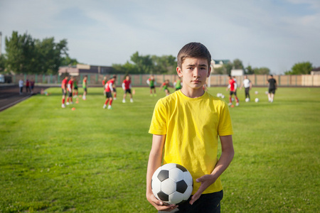 严重的十几岁的男孩用足球球在他的手对 b