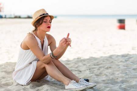 时尚的女人坐在沙滩上，在夏天