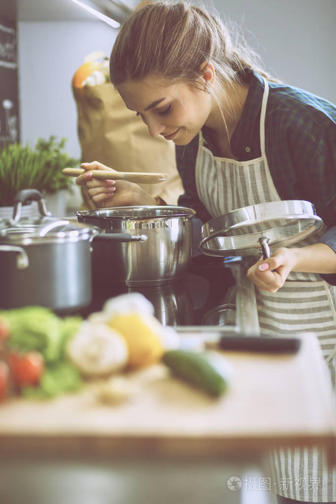 她厨房站附近炉子做饭的年轻女人