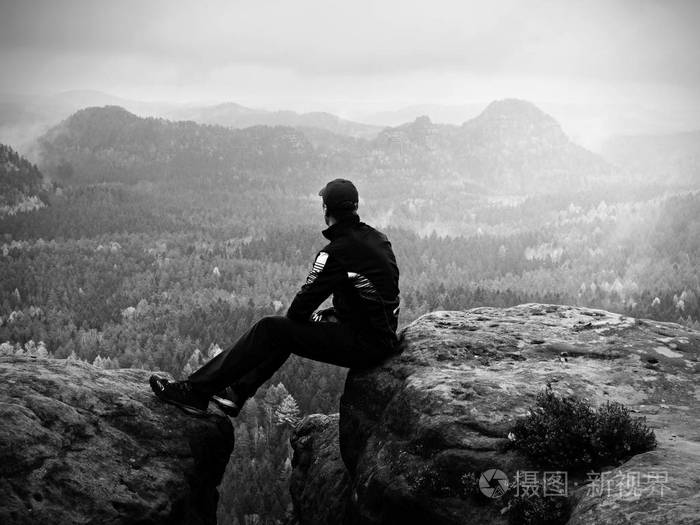 黑衣男人坐在裂纹岩石帝国.忧郁有雾的日子