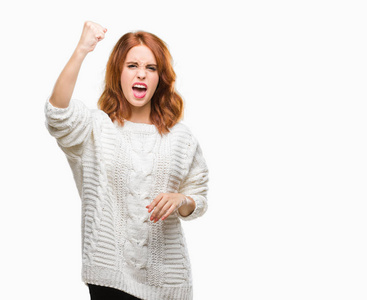 年轻美丽的女人在与世隔绝的背景下穿着冬衣愤怒而疯狂的举起拳头