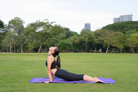 妇女锻炼瑜伽在公园准备好健康生活方式在自然