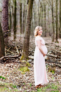 幸福的怀孕女人享受在森林里走