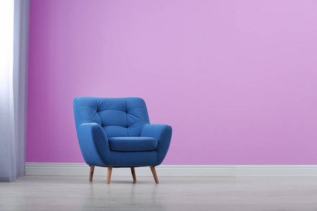 时尚舒适的扶手椅靠近彩色墙壁