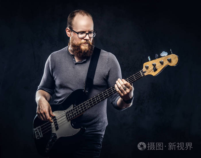 红胡子的男音乐家戴着戴着眼镜的灰色 t恤在电吉他上演奏.