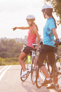 两位女运动员站在一起骑自行车休息的美丽画像