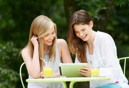 两名少女在户外咖啡厅使用数码平板电脑