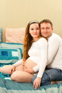 幸福的孕妇和丈夫在家里的沙发上。