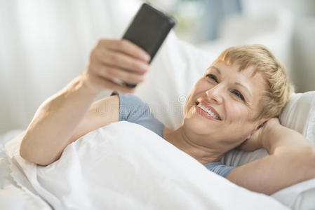 躺在床上用手机的妇女