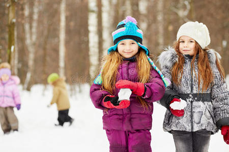 两个女朋友手持雪球站在冬季公园里