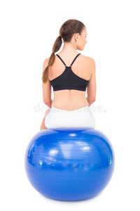 健身女子坐在健身球上的后视图