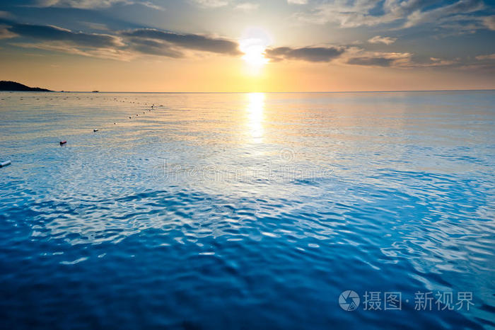 冉冉升起的太阳平静的海面照亮了云层