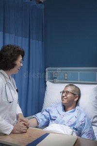 微笑的医生检查躺在病床上，手牵着手的病人