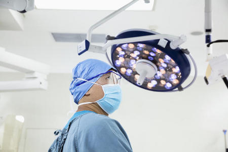 手术室戴手术面罩和眼镜的外科医生侧视图
