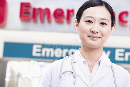 医院外微笑的女医生画像，背景是急诊室标志