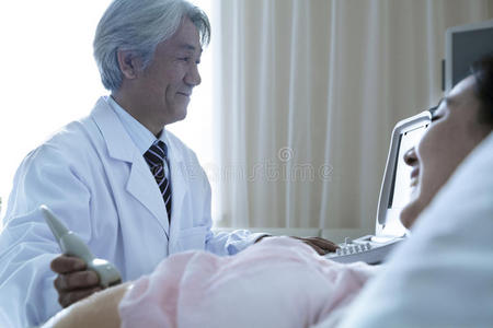 医生在医院给一个仰卧的孕妇做超声波检查
