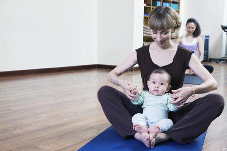 妈妈和宝宝盘腿坐在瑜伽课上练瑜伽