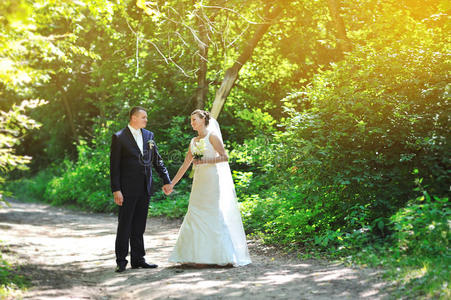 快乐的新郎新娘在夏日公园散步