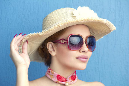 蓝色背景下戴帽子的漂亮时尚女孩的肖像照片