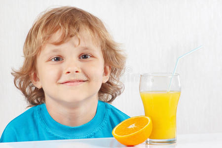 小男孩拿着一杯新鲜果汁和桔子