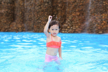 漂亮的小女孩在游泳池在户外玩耍