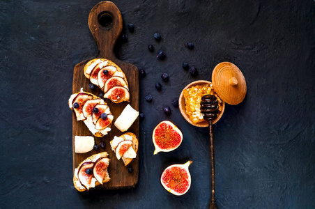 三明治与新鲜无花果, 山羊奶酪, 蜂蜜和蓝莓在木板上。素食, 天然产品概念