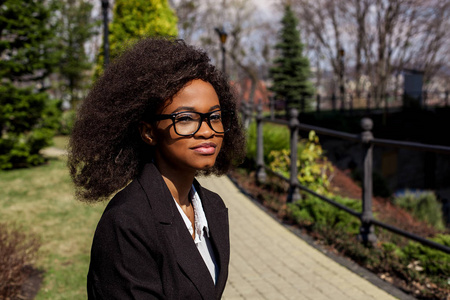 美丽的黑人女商人在公园里的肖像.女人戴着眼镜,乌黑的卷发照片