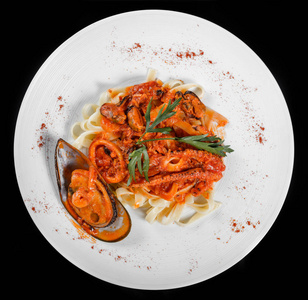 面条面食与海鲜, 贻贝, 章鱼, 牡蛎, 番茄酱和草药, 在碗孤立的黑色背景。意大利菜。顶部视图