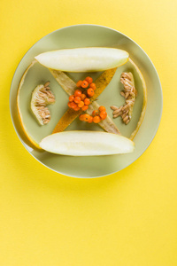 在黄色背景下的瓜片和内脏。皮瓜放在绿色盘子里。在彩色背景上的罗恩浆果。素食。健康的生活方式。流行艺术