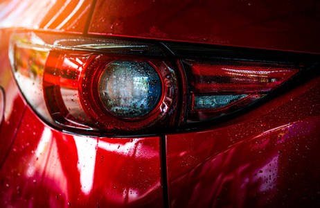红色紧凑型 Suv 汽车与体育和现代设计是洗涤用水。汽车护理服务的经营理念。用高压水喷雾清洗后的车盖上水滴。豪华灯