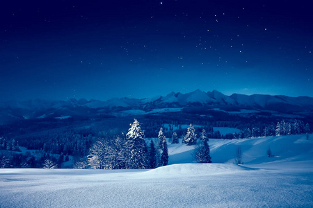 下雪的冬夜。迷人的夜景。天空与星在下雪的山和谷